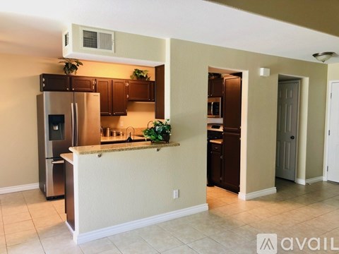 A kitchen with a refrigerator, microwave, and a counter with a plant on it.