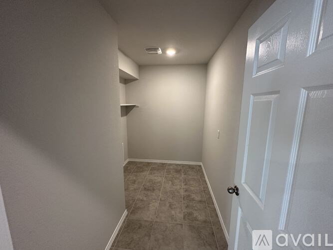 A hallway with a white door and a tiled floor.