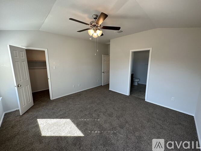 A room with a ceiling fan and carpeted floor.