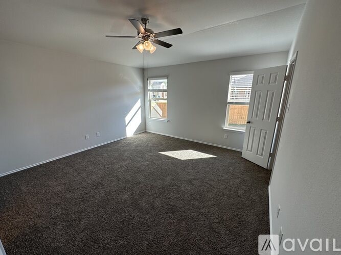 A room with a ceiling fan and a door leading to another room.