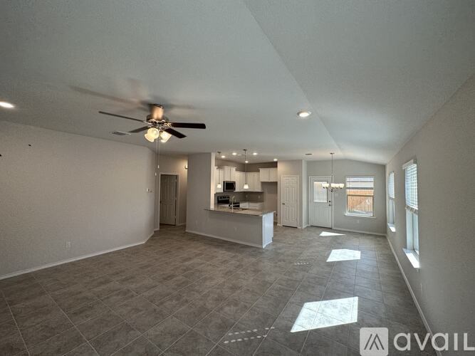 A spacious room with a ceiling fan and a kitchen area in the background.