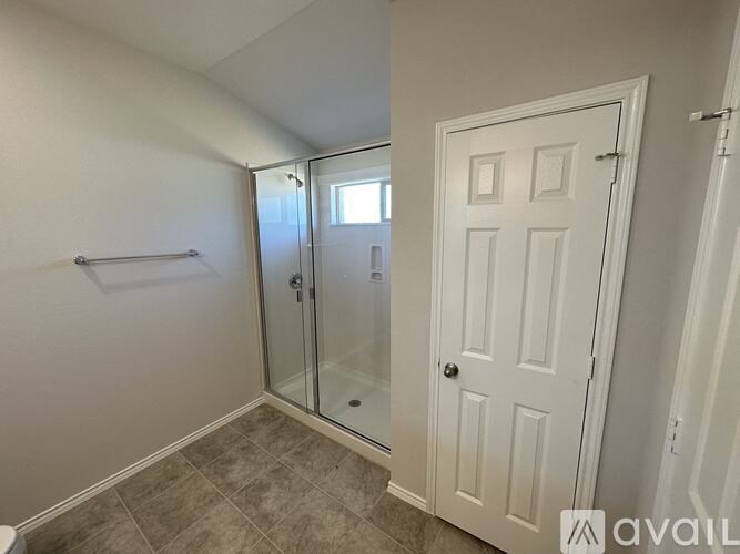 A bathroom with a white door and a glass shower stall.