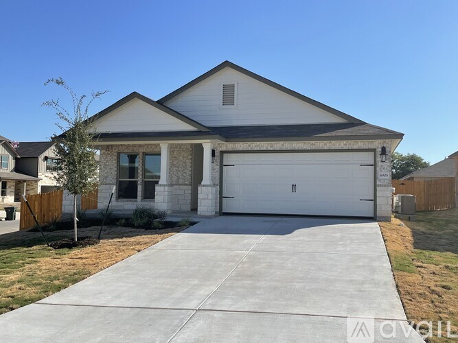 A two-car garage is attached to a white house with a brown roof.