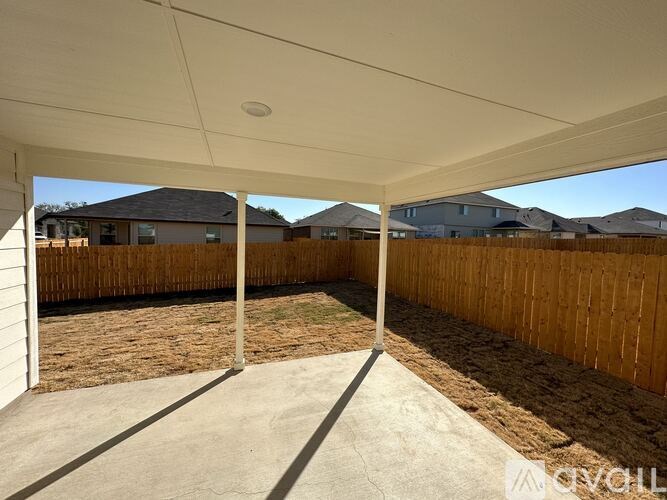 A covered patio area with a white ceiling and wooden fence.