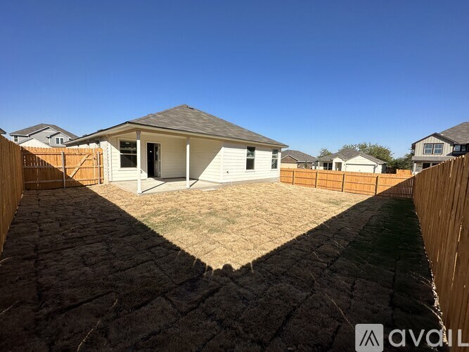 A house with a white exterior and a brown roof is surrounded by a wooden fence.