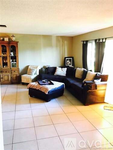 A living room with a black couch and a wooden cabinet.