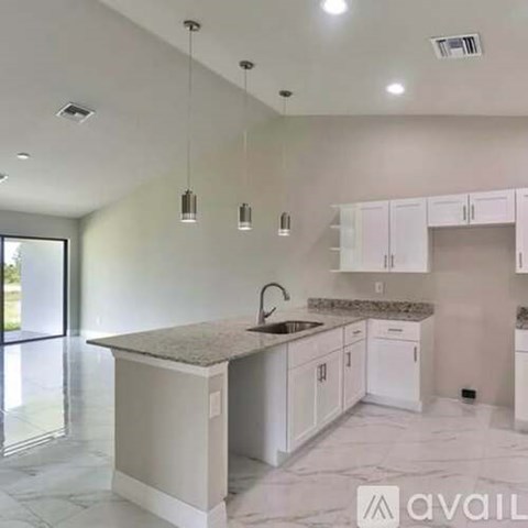 A kitchen with white cabinets and a marble countertop.