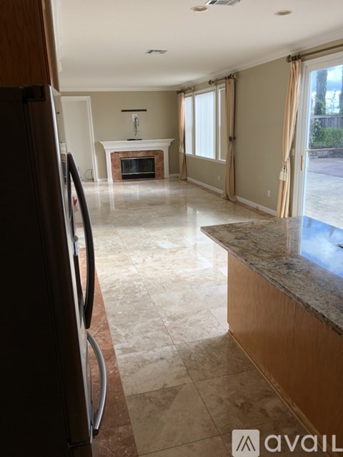 A kitchen with a refrigerator and a fireplace in the background.