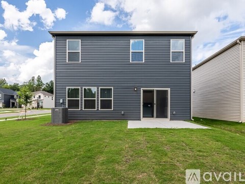 A grey house with a white door and windows is for sale.
