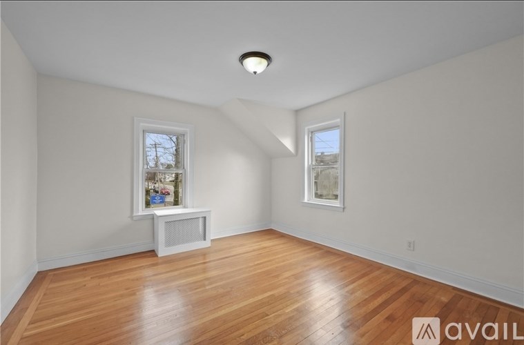 A room with wooden floors and two windows.