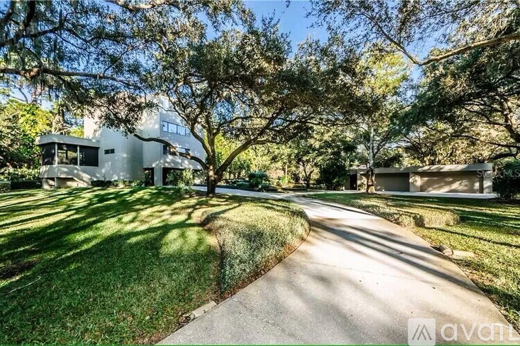 A house with a driveway and trees in front of it.