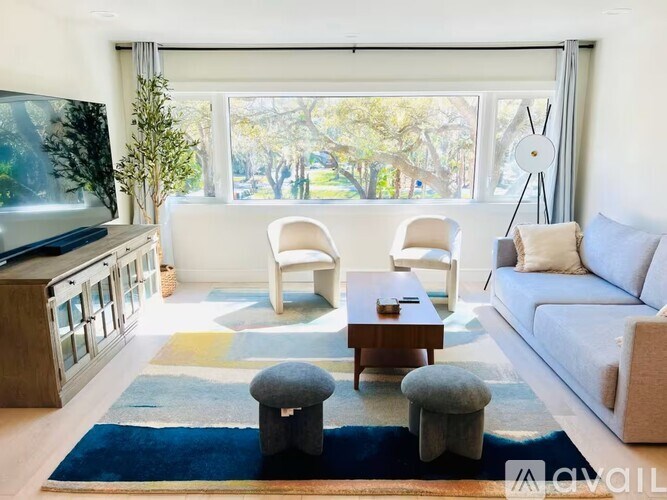 A living room with a couch, chairs, and a television.