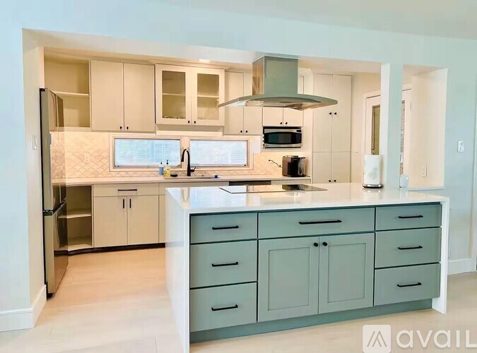 A kitchen with a white counter top and a stainless steel refrigerator.