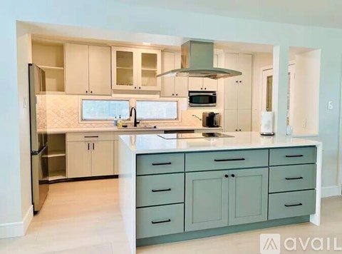 A kitchen with a white counter top and a stainless steel refrigerator.
