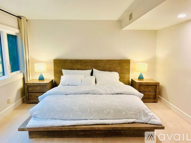 A bedroom with a large bed and two nightstands with lamps.