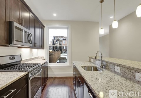 A kitchen with dark brown cabinets and a granite countertop.