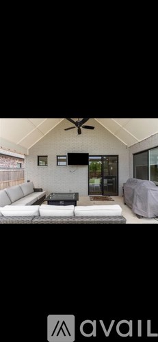 A modern living room with a white sofa and a flat-screen TV mounted on the wall.