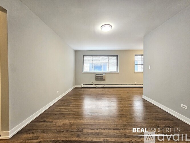 A spacious room with wooden flooring and a window.