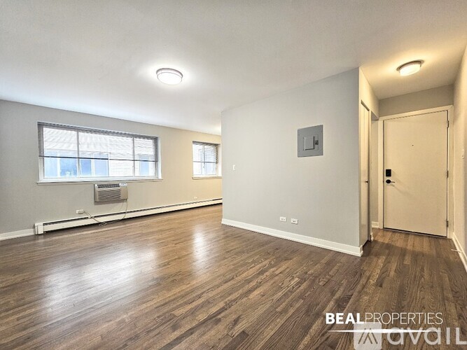 A room with wooden flooring and a window with a view of buildings outside.
