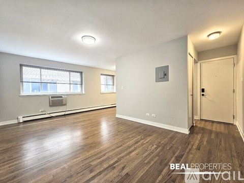 A room with wooden flooring and a window with a view of buildings outside.