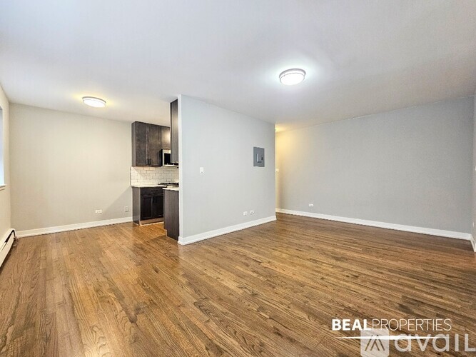 A spacious room with wooden flooring and a white wall.