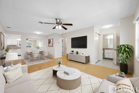A living room with a white couch and a television on the wall.