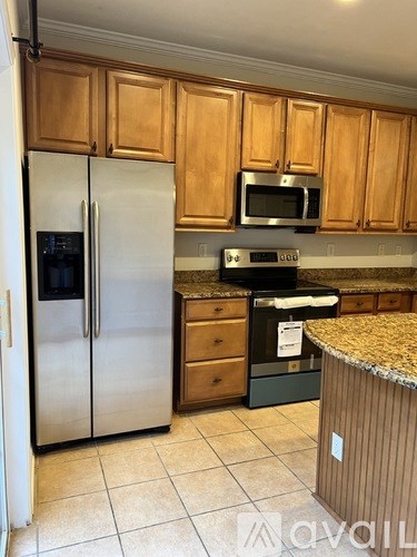 A kitchen with wooden cabinets and a stainless steel refrigerator.