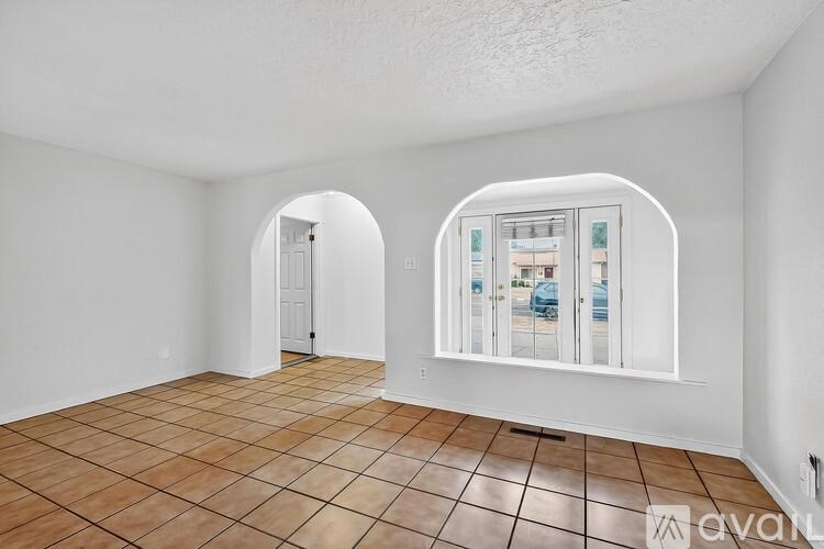 A room with a tiled floor and a large arched doorway leading to another room.
