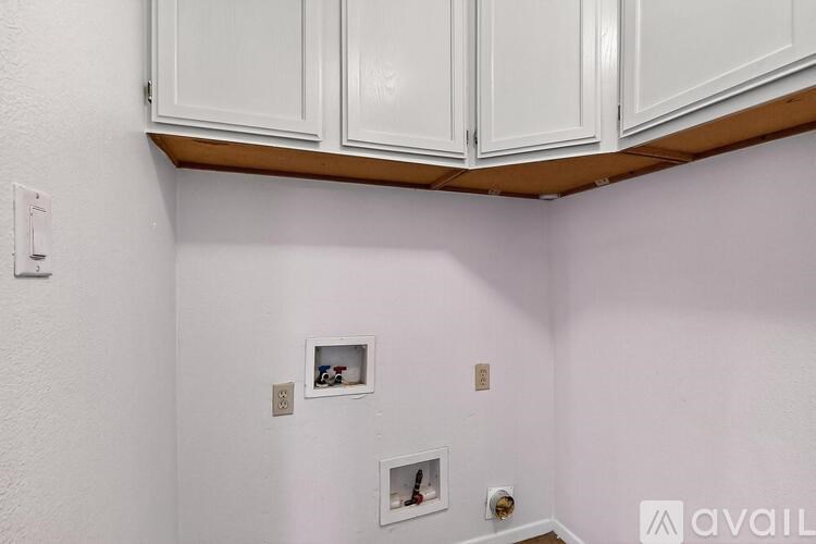 A kitchen with white cabinets and a white wall.