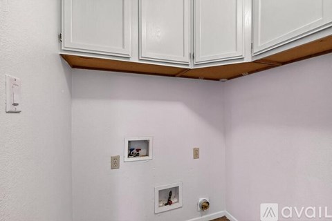A kitchen with white cabinets and a white wall.