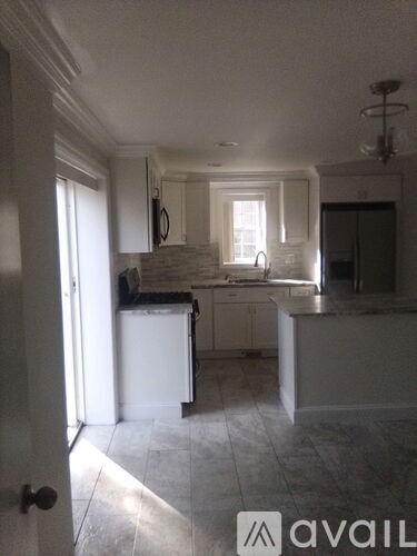 A kitchen with white cabinets and a black counter top.