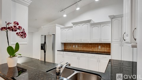 A kitchen with white cabinets and a marble countertop.
