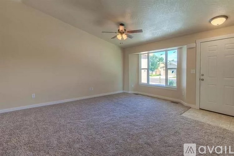 A room with a carpeted floor and a ceiling fan.