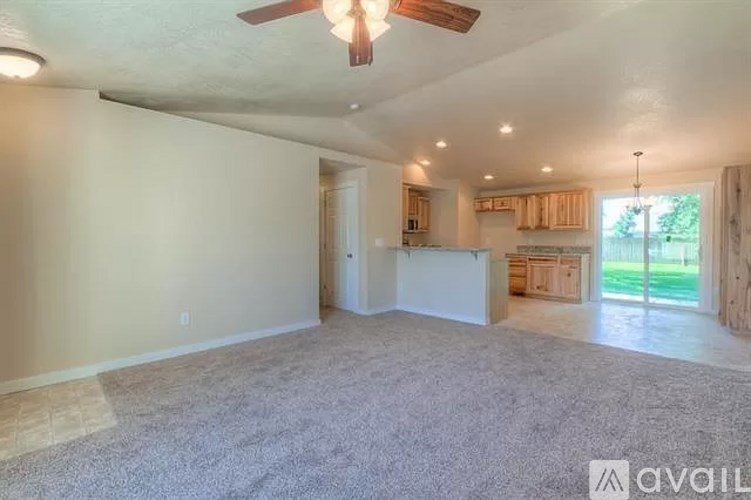 A spacious room with a ceiling fan and carpeted floor.