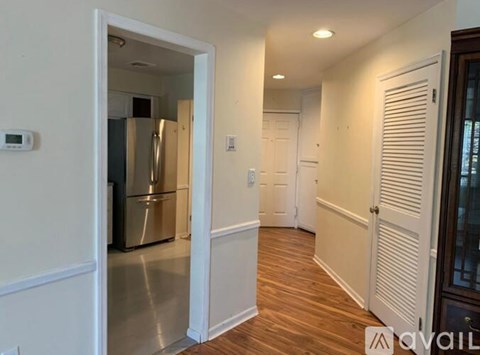 A kitchen with a refrigerator and a hallway with a door on the right.