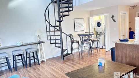 A living room with a spiral staircase and a dining table with chairs.