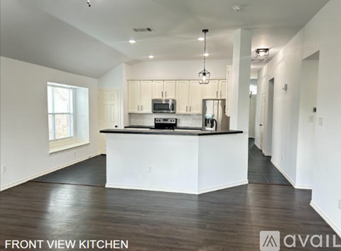 A spacious kitchen with white cabinets and a black countertop.