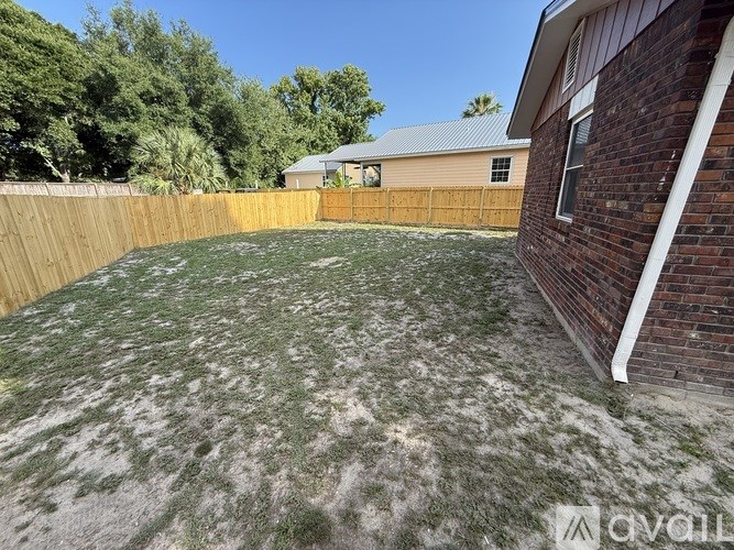 A backyard with a wooden fence and a house with a brick wall.