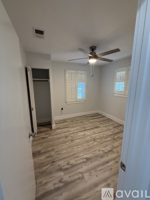 A room with a ceiling fan and wooden flooring.