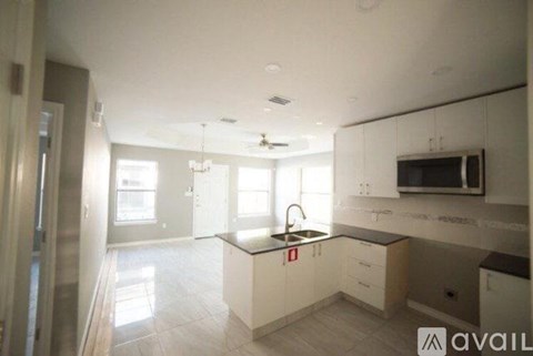 A modern kitchen with white cabinets and a black countertop.