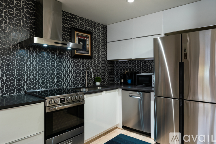 A modern kitchen with a stainless steel refrigerator and black and white tiled backsplash.