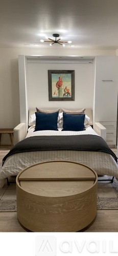 A bedroom with a bed, a ceiling fan, and a painting on the wall.