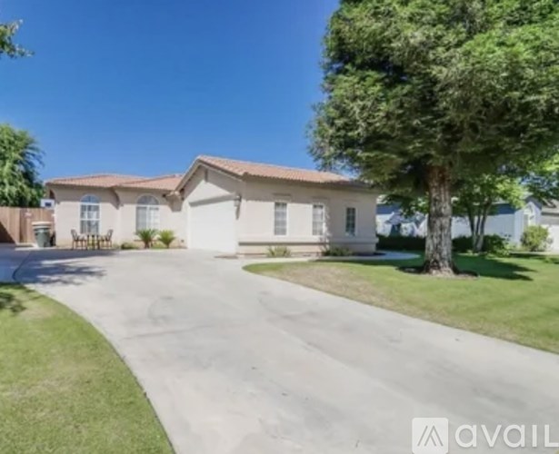 A house with a driveway and a tree in front of it.