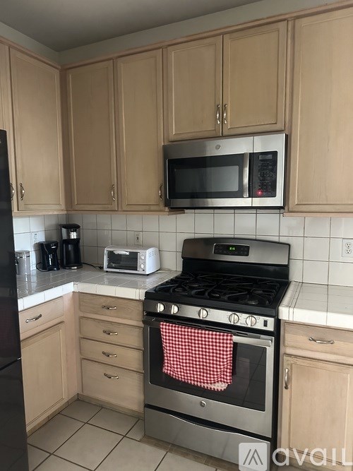 A kitchen with a black refrigerator, a silver oven, and a black microwave.