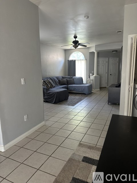 A living room with a couch and a ceiling fan.