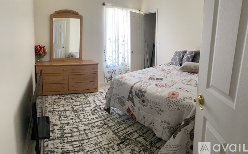 A bedroom with a bed, dresser, and mirror.