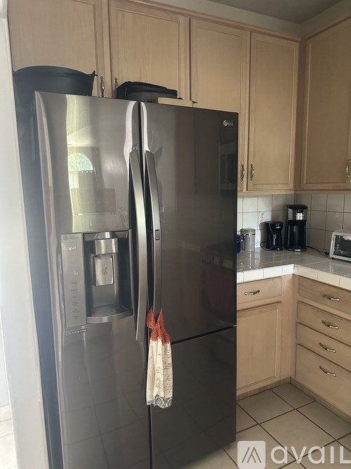A black refrigerator with a water and ice dispenser in a kitchen.
