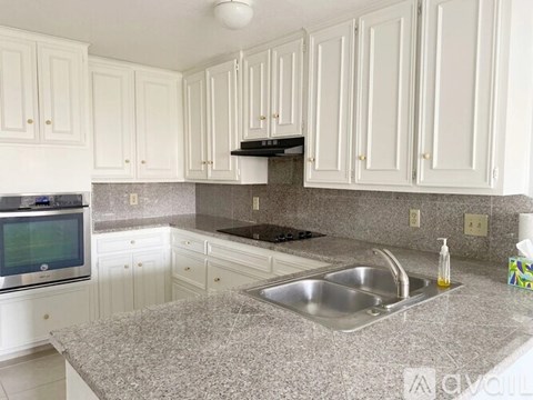A kitchen with white cabinets and a granite countertop.