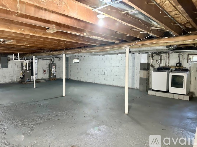 A spacious, unfinished basement with concrete floors and exposed ceiling beams.