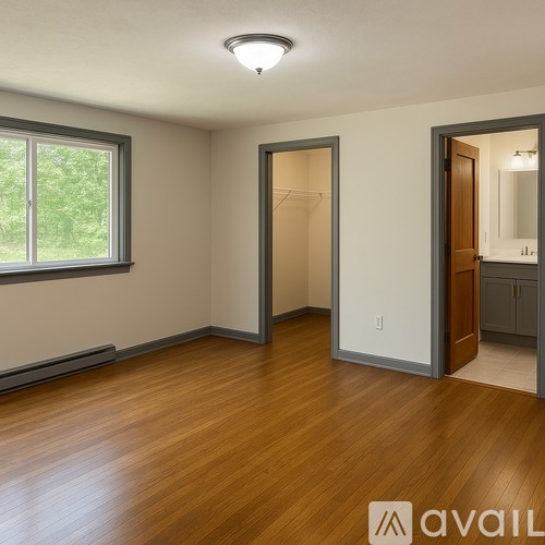 A room with wooden floors and a window with a view of trees.
